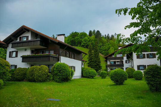 Cozy alpine houses with wooden roofs lost in green rainy valley among mountains. Little german town Fussen.