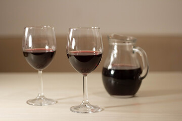 Two glasses and a decanter of red wine are on the table