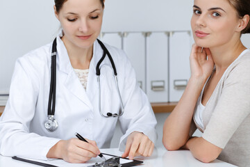 Doctor and patient are sitting and discussing health examination results in clinic office. Health care, medicine and good news concepts