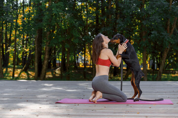 morning exercises with your pet. young slender woman practices yoga and pilates in a summer park....