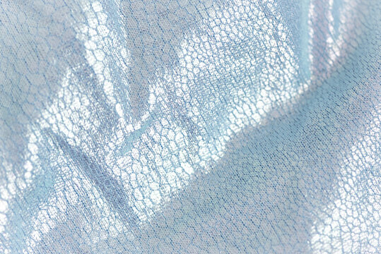 Creased textile texture, background template. Shine fabric light blue drapery. Sheene sharkskin fabrics for fashion dress.