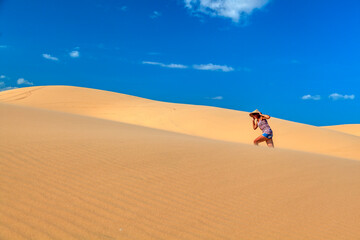 Fototapeta na wymiar beautiful girl in the desert runs barefoot on the top of the hill in the sand