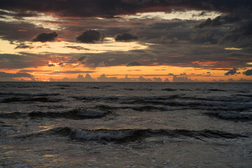Dark waves and after sunset light in the dark clouds on baltic coast