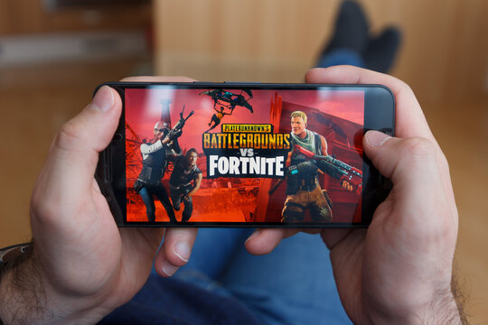 LOS ANGELES, CALIFORNIA - JUNE 3, 2019: Lying Man holding a smartphone and compares PUBG and Fortnite games on the smartphone screen. An illustrative editorial image.