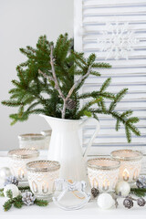Weihnachtsdekoration mit Tannenzweigen in Vase und Windlichtern