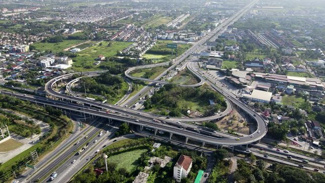 4K. Aerial view of road interchange or highway intersection with busy urban traffic speeding on the road. Junction network of transportation taken by drone.