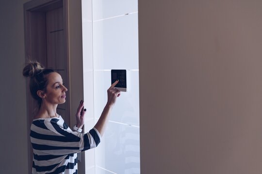 Smiling woman entering code on keypad of home security alarm. Home security.