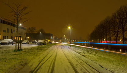 First snow at night in a residential street with parked cars along a canal in winter, Almere, Flevoland, The Netherlands, January 16, 2020