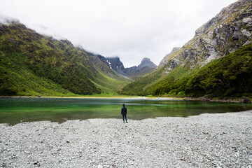 Fototapeta na wymiar Person stand in front of Emily Peak in Lake Mackenzie at the famous Routeburn Track in Summer, Fjordland National Park, Southland, New Zealand
