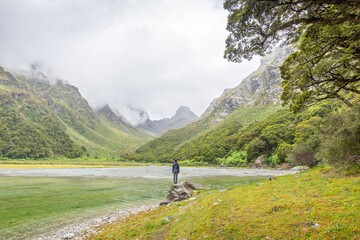 Fototapeta na wymiar Person stand in front of Emily Peak in Lake Mackenzie at the famous Routeburn Track, Fjordland National Park, Southland, New Zealand