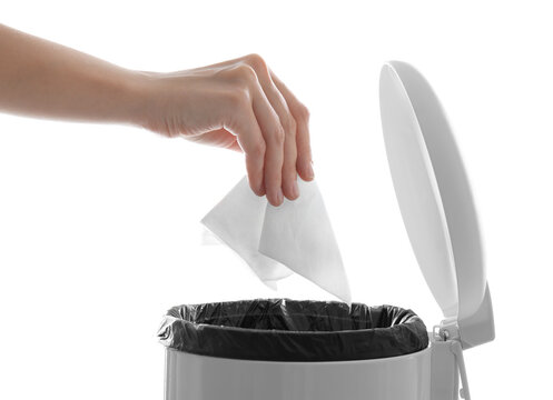 Woman putting paper tissue into trash bin on white background, closeup