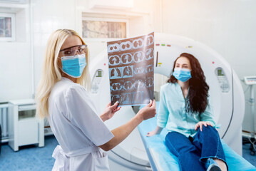 Radiologist with a female patient wearing protective masks examining a CT scan