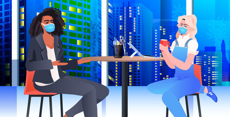 mix race businesspeople in masks discussing during coffee break business women couple sitting at table night cityscape background horizontal portrait vector illustration