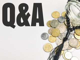 Top view text Q AND A written on white background with coins,glass jar and prayer beads.Islamic...