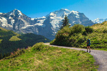 Fototapeta na wymiar Hiker woman with backpack on the hiking trail, Murren, Switzerland