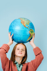 Red-haired girl with a globe in her hands, holding over her head. 