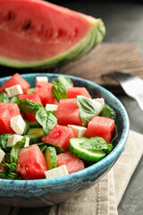 Delicious salad with watermelon served on black table, closeup