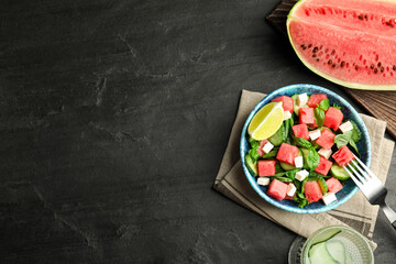 Delicious salad with watermelon served on black table, flat lay. Space for text