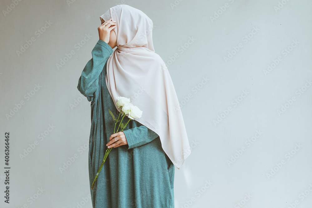 Wall mural young muslim woman standing and posing while covering her face