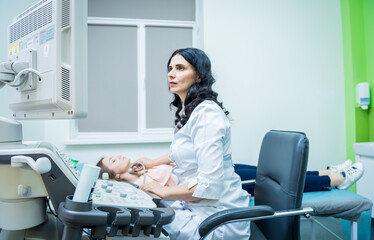 Doctor using ultrasound scanning machine for examining a thyroid of woman