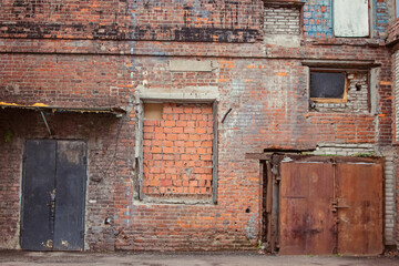 Obraz na płótnie Canvas A large fragment of the brick wall of the old factory with bricked-up parts and windows
