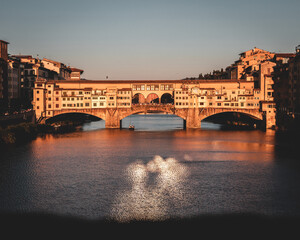 view of the famous Ponte Vecchio bridge over the Arno river before sunset.