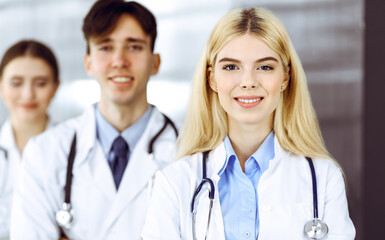 Group of three young doctors standing as a team with arms crossed in modern clinic and ready to help patients. Medicine concept