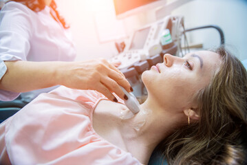 Obraz na płótnie Canvas Doctor using ultrasound scanning machine for examining a thyroid of woman