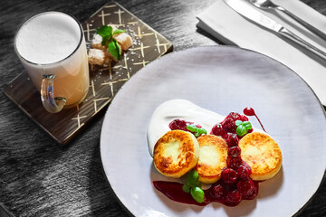 Pancakes with sour cream and jam on a white plate. Tasty breakfast. Cane sugar and coffee with milk