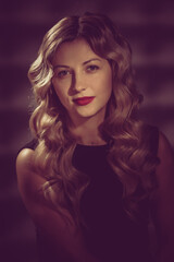 Fototapeta premium Fashion studio portrait of beautiful girl with blonde curly hair. image toned in warm colors in retro style