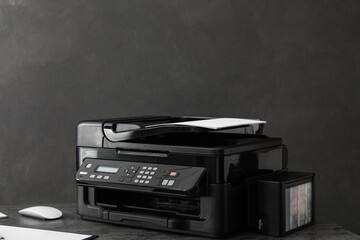 Modern printer with paper on grey table at workplace
