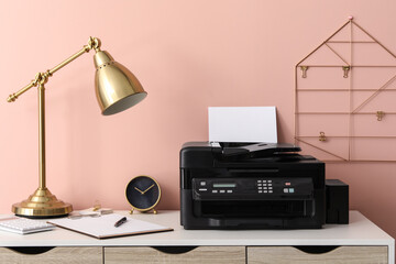 New modern printer with paper on white table at workplace