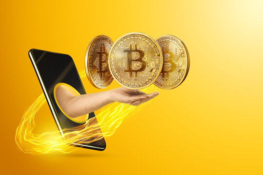 The hand crawling out through the smartphone holds, offers bitcoin coins, yellow background. Crypto currency concept, blockchain technology, money of the future. Copy space.