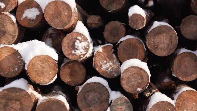 Closeup view 4k video of many snowy stacked firewoods laying outdoor in winter