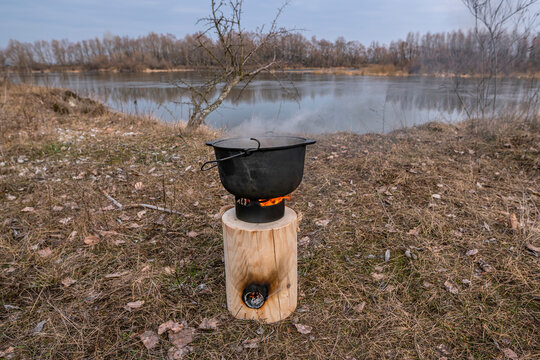 Cauldron cooking on Finnish (Swedish) log candle at river coast