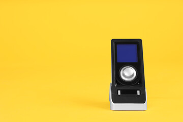 Modern remote for audio speakers on yellow background, space for text