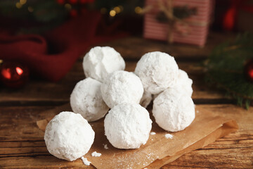 Tasty snowball cookies and Christmas decorations on wooden table, closeup