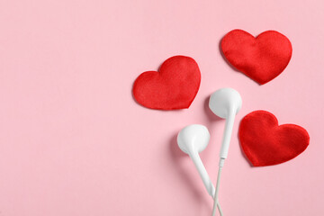 Modern earphones and red hearts on pink background, flat lay with space for text. Listening love music songs