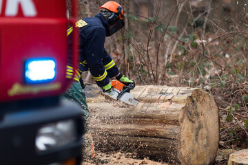 Feuerwehrmann mit Kettensäge beseitigt Sturmschaden