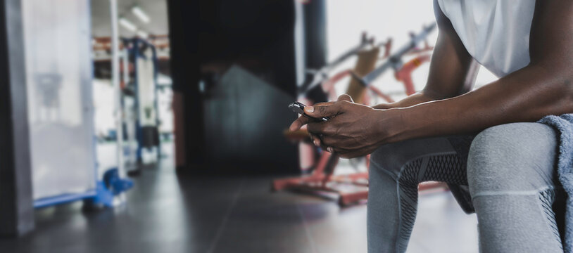 Black muscle athlete male in fitness studio gym rest and using smart phone, Healthy technology concept, Banner with copy space