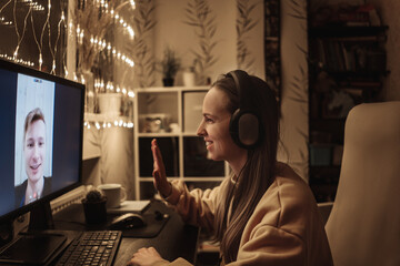 Woman making video call to man using computer, looking at screen with virtual web chat, close up. Wife and husband festive talk. Garland on background.