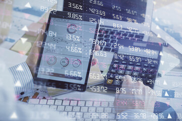 Double exposure of man's hands holding and using a digital device and forex graph drawing. Financial market concept.