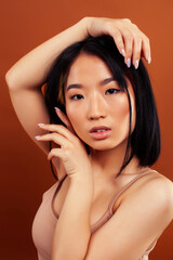 Fototapeta premium young pretty asian woman cheerful smiling posing on warm brown background, lifestyle people concept