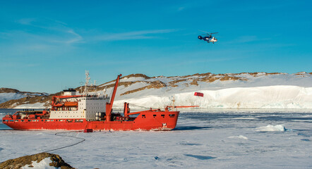 Unloading of the cargo ship by the helicopter on the coast.