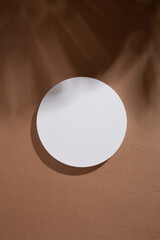 White round podium on brown background with tropical leaf shadow. Flat lay,top view. 