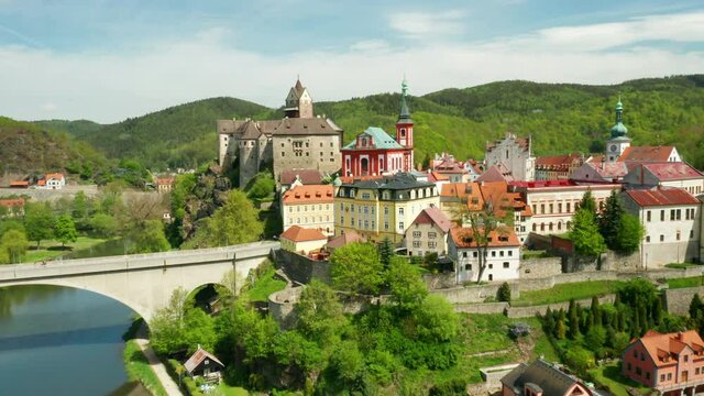 Flight over Loket castle, surrounded by river Ohri and small houses on a river shore, near Kariovy Vary, Czech Republic.