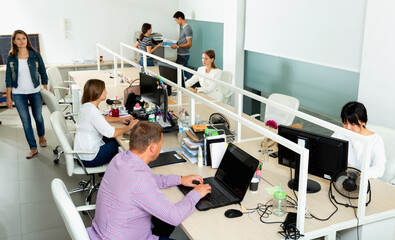 Positive cheerful smiling International business team working and communicating together in modern coworking space