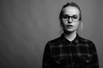 Young beautiful woman with blond hair wearing eyeglasses against gray background