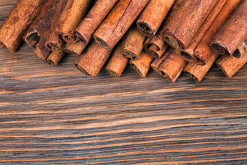 Stack of cinnamon sticks on a wooden background. Macro photography of spices. Top view.