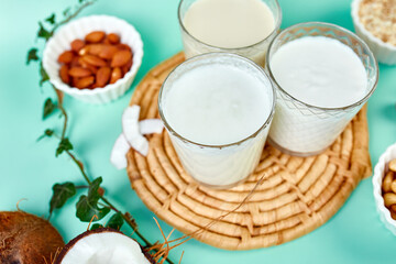 Various vegan plant based milk and ingredients, non-dairy milk, alternative types of vegan milks in glasses on a blue background with copy space